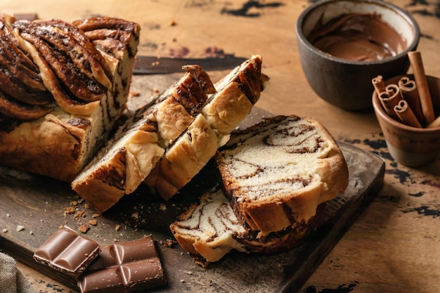 Babka de chocolate ou pão de brioche Massa de fermento doce caseira pão de redemoinho de chocolate fatiado em tábua de madeira