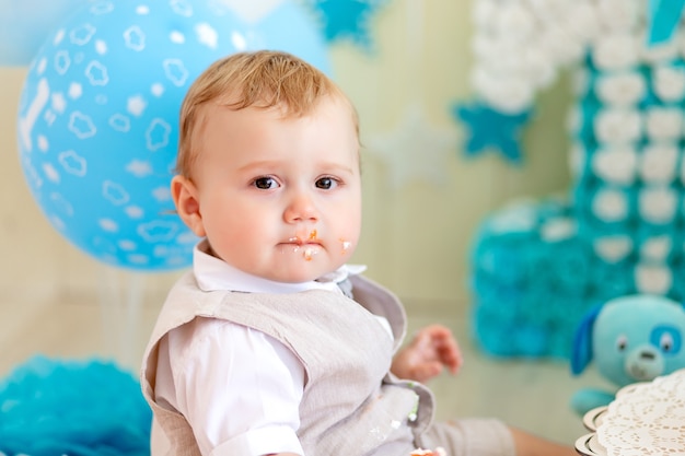 Baby 1 Jahr in einem Fotostudio mit Kuchen und Luftballons, Geburtstag eines Kindes 1 Jahr, Baby isst Kuchen