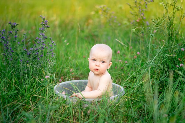 Baby 10 Monate alt badet in einem Becken im Gras im Sommer