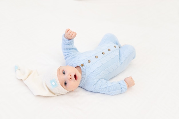 Baby auf dem Bett in einer Schlafmütze. Textilien und Bettwäsche für Kinder. Babys Morgen