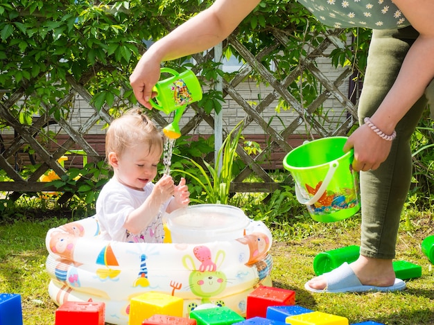 Baby badet an einem warmen Sommertag in einem aufblasbaren Kinderbecken