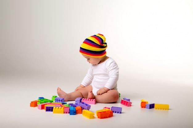 Baby Boy 9 meses jugando con un constructor multicolor en una pared blanca