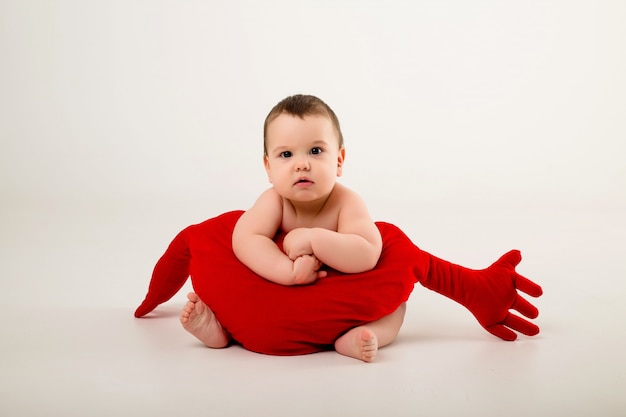 Baby Boy 9 meses sonriendo y sosteniendo una almohada roja en forma de corazón