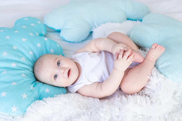Baby Boy acostado en la cama antes de ir a la cama lindo riendo seis meses sonriendo pequeño bebé