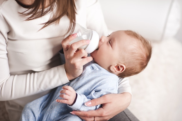 Baby Boy bebiendo leche de botella sosteniendo por madre