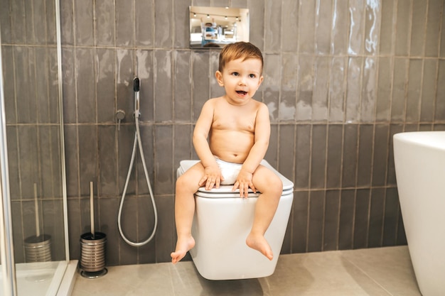 Baby Boy con la boca abierta sentado en el WC