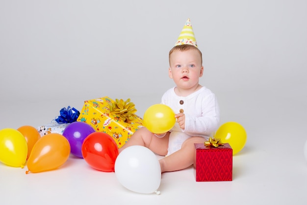 Baby Boy celebra cumpleaños con globos y regalos sobre un fondo blanco en el estudio