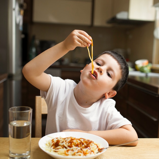 Foto baby boy comiendo pasta con las manos