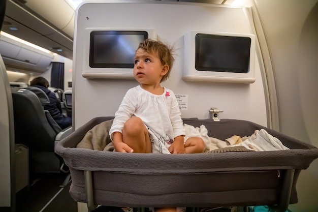 Baby Boy se despierta después de dormir en el moisés en el avión. pasajero infantil a bordo. primer vuelo