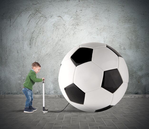 Foto baby boy divertido hinchado un gran balón de fútbol