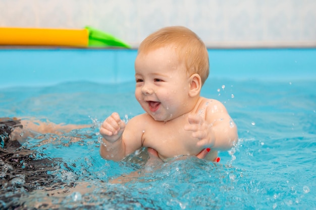 Baby Boy entrena para nadar en la piscina con un entrenador