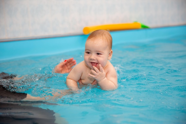 Baby Boy entrena para nadar en la piscina con un entrenador