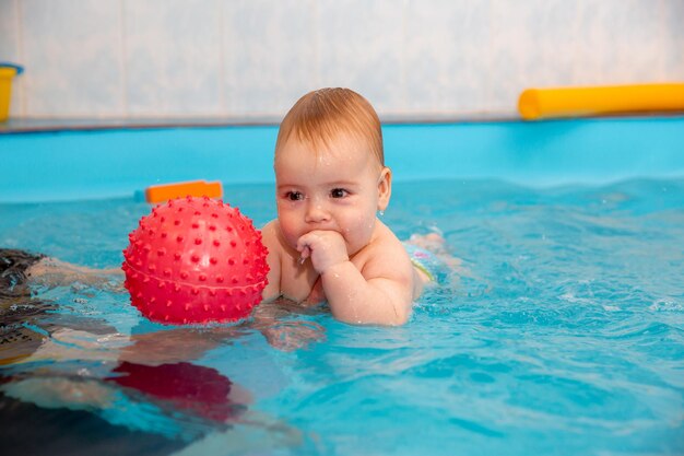 Baby Boy entrena para nadar en la piscina con un entrenador