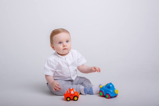 Baby Boy jugando con coches de juguete sobre fondo blanco.