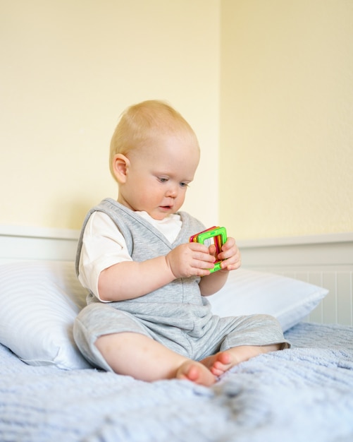 Baby Boy jugando con juguetes de construcción magnética mientras está sentado en la cama