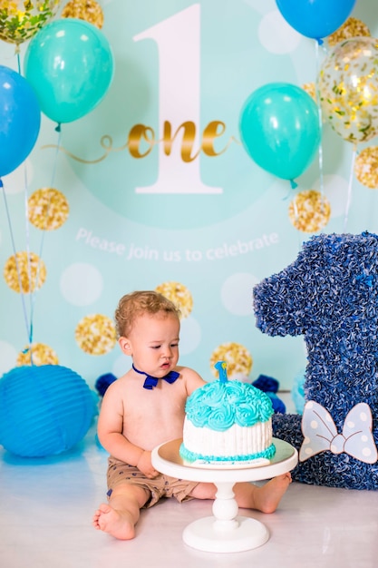 Baby Boy jugando con un pastel durante la fiesta de cumpleaños de cake smash