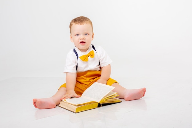 Baby Boy con un libro sentado sobre un fondo blanco.