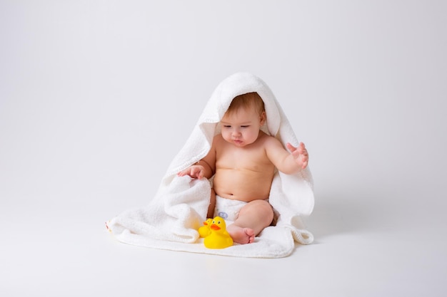 Baby Boy en un pañal sentado sobre un fondo blanco con una toalla y patos de goma concepto de baño