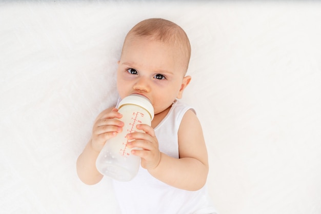 Baby Boy en ropa blanca sentado en una cuna