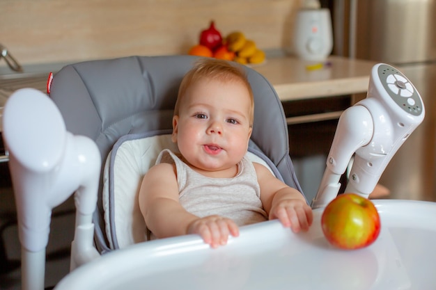 Baby Boy sentado en la guardería comiendo una manzana en la cocina