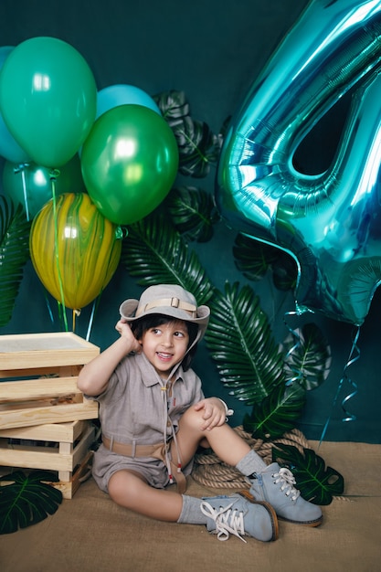 Baby boy sostiene un globo en casa sobre un fondo verde en su cumpleaños