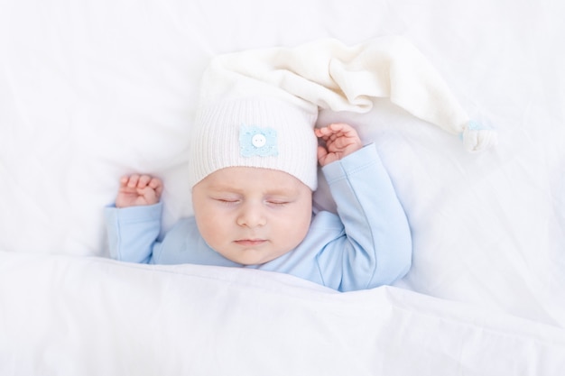 Baby, das auf dem Bett schläft, das auf dem Rücken unter der Decke liegt, gesunder Neugeborenenschlaf