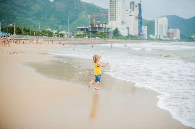 Baby, das auf dem Sandstrand nahe dem Meer geht. Nettes kleines Kind am tropischen Sandstrand.