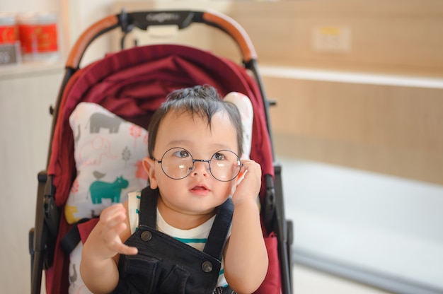 Baby, das Brillen trägt, die im modernen Kinderwagen sitzen. Reisen mit kleinen Kindern. Transport für Familie mit Kleinkind.