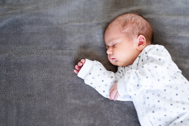 Baby, das die ersten Lebenstage schläft. Nettes kleines neugeborenes Kind, das friedlich schläft.