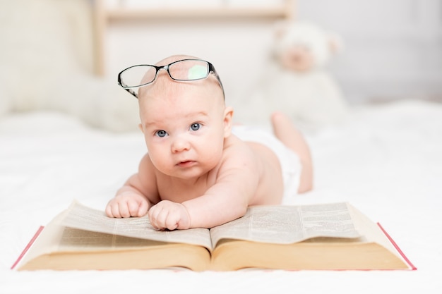 Baby, das ein Buch liest oder es im Kindergarten-, Lern- und Entwicklungskonzept betrachtet