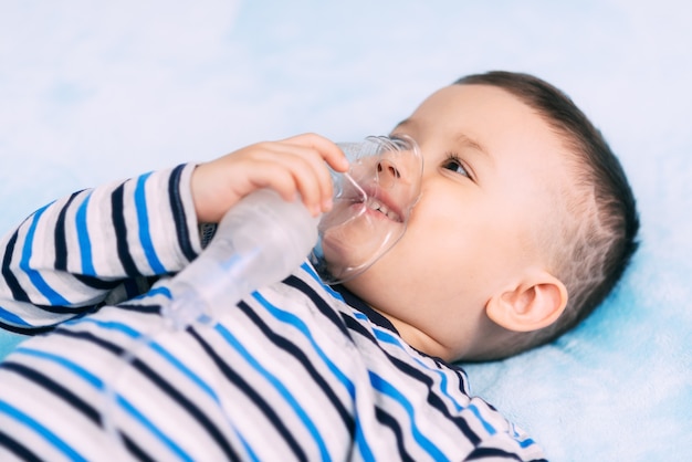 Baby, das eine Maske Wegfahrsperre Sprühgerät hält, während ein Atemzug