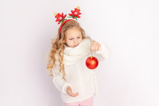 Baby, das einen roten Weihnachtsball auf Weiß hält