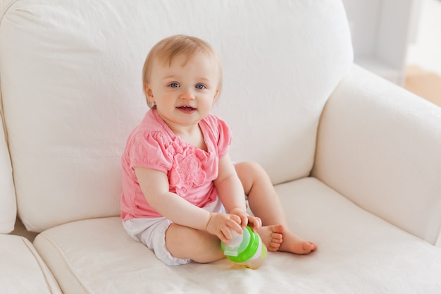 Baby, das mit einem Ball beim Sitzen auf einem Sofa spielt