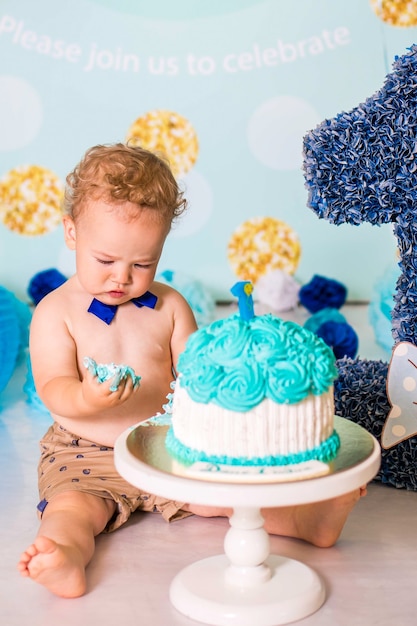 Baby, das mit einem Kuchen während der Kuchen zerschmettert Geburtstagsfeier spielt