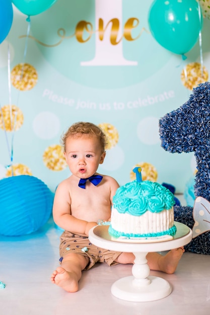 Baby, das mit einem Kuchen während der Kuchen zerschmettert Geburtstagsfeier spielt