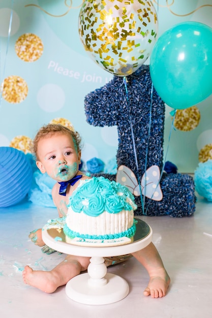 Baby, das mit einem Kuchen während der Kuchen zerschmettert Geburtstagsfeier spielt