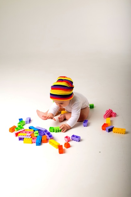 Baby, das mit einem mehrfarbigen Konstrukteur auf einer weißen Wand spielt