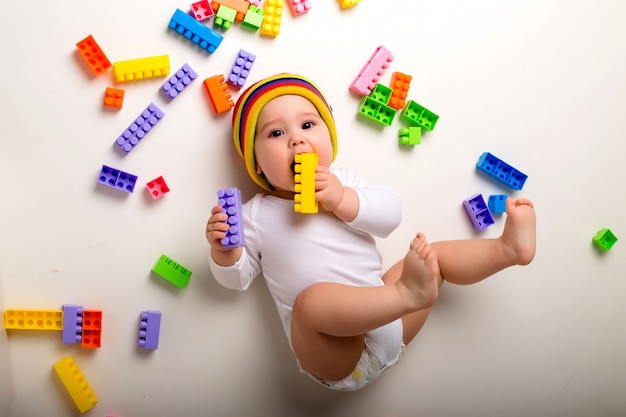 Baby, das mit einem mehrfarbigen Konstrukteur auf einer weißen Wand spielt