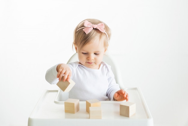 Baby, das mit Holzwürfeln durch linke Hand spielt. Spielendes Kleinkind lokalisiert auf weißem Hintergrund. Spiele für Kinder, Vorschulerziehung. Nahaufnahme, selektiver Fokus