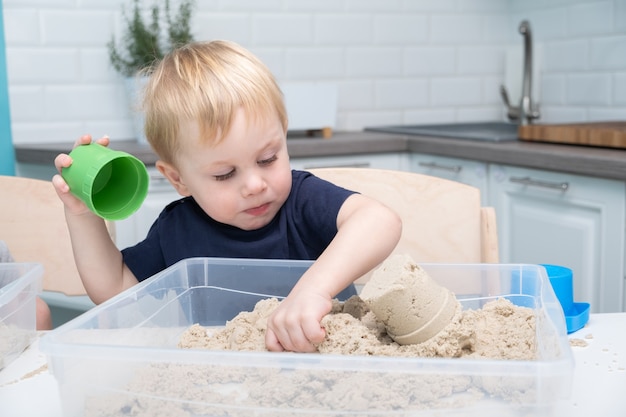 Baby, das mit kinetischem Sand zu Hause spielt.