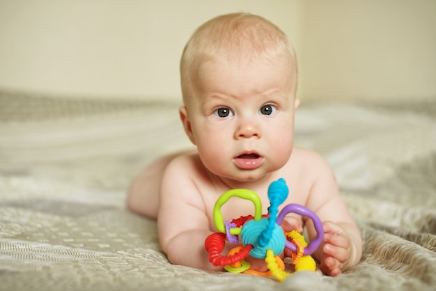 Baby, das mit Spielzeug auf dem Bett zu Hause spielt