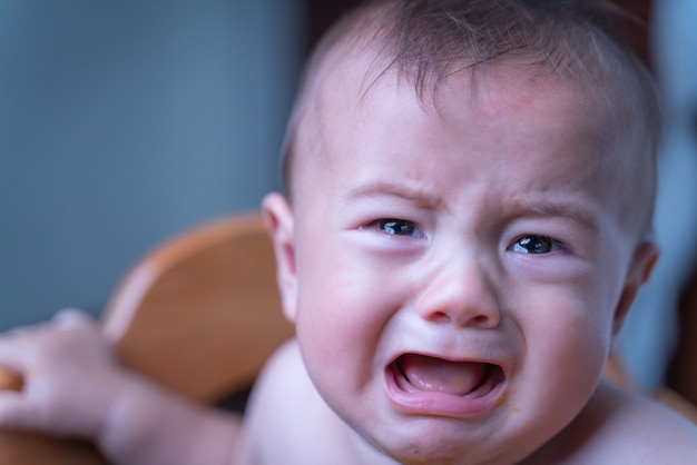 Foto baby, das traurig und im raum weinend sitzt