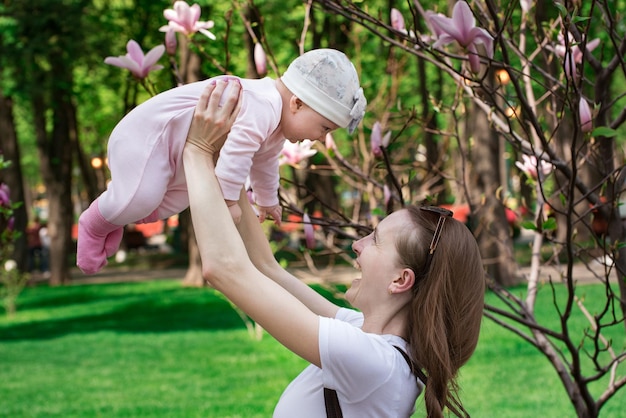 Baby fliegt in Mutterhänden Mutter und kleine Tochter spielen auf dem Hintergrund der Natur