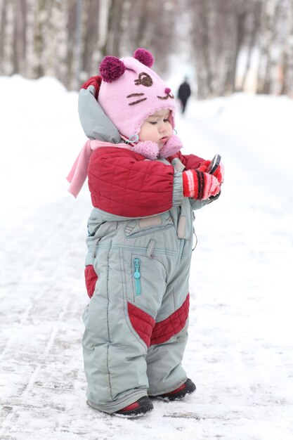 Baby für einen Spaziergang im Winter mit einem Telefonanruf