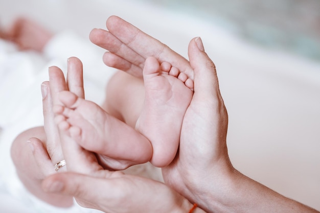 Baby-Füße in den Händen der Mutter Tiny Newborn Baby's Füße auf weiblich Geformte Hände closeup Mutter und ihr Kind Happy Family-Konzept Schönes konzeptionelles Bild der Mutterschaft