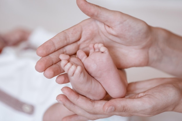 Baby-Füße in den Händen der Mutter Tiny Newborn Baby's Füße auf weiblich Geformte Hände closeup Mutter und ihr Kind Happy Family-Konzept Schönes konzeptionelles Bild der Mutterschaft