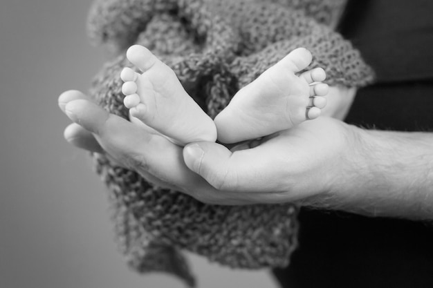 Baby-Füße in den Händen des Vaters Tiny Newborn Baby's Füße auf männliche Hände Nahaufnahme Dad und sein Kind Happy Family-Konzept Schönes konzeptionelles Bild der Elternschaft