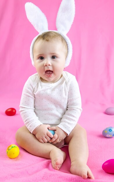 Baby gekleidet wie ein Hase mit Ostereiern für Osterferien