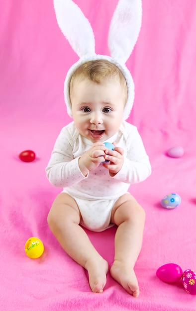 Baby gekleidet wie ein Hase mit Ostereiern für Osterferien