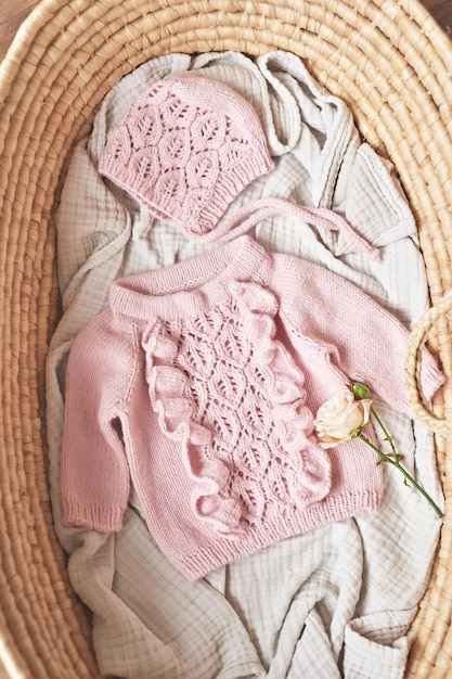 Baby gestrickte Kleidung im Weidenkorb Vorbereitung für die Geburt